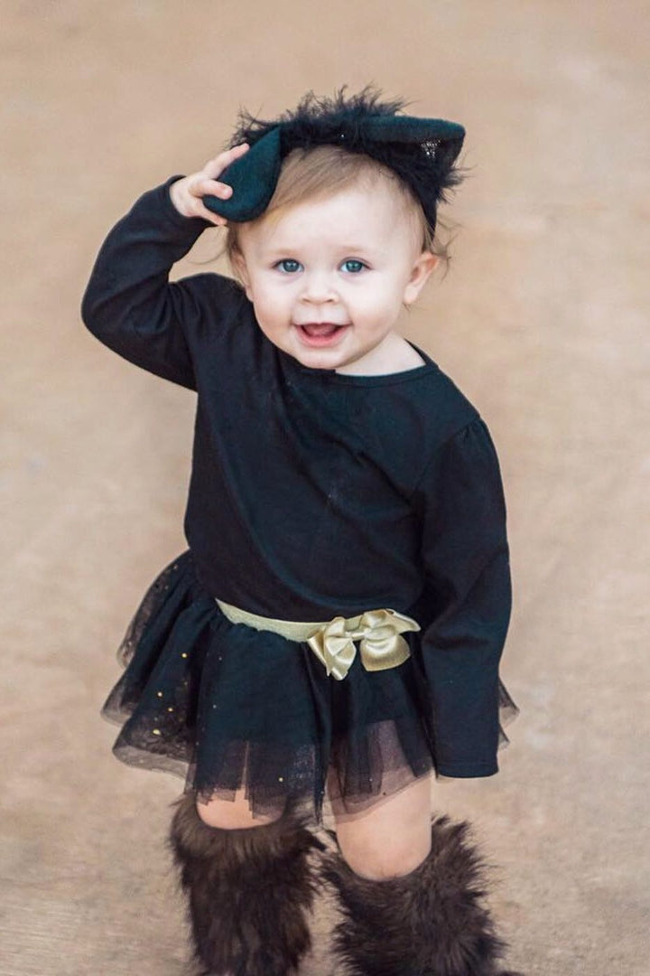 Toddler in a black cat costume with cat ears, a black tutu and fuzzy leg warmers