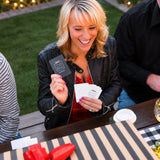 A woman smiling at her cards during a Christmas gift exchange game after dinner