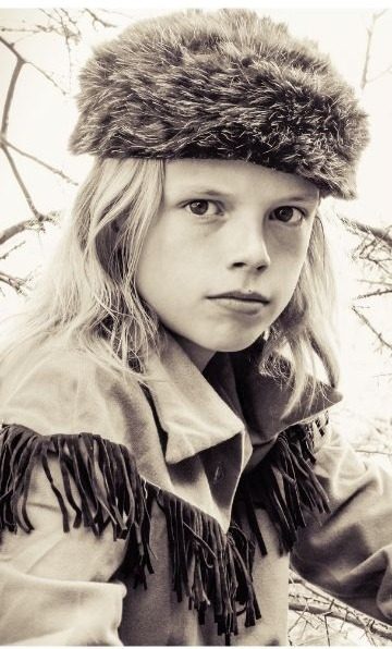 Boy in a Davy Crockett costume with a fur cap and fringed jacket, in black and white