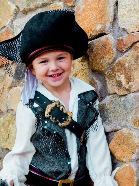 Smiling little pirate against a stone wall