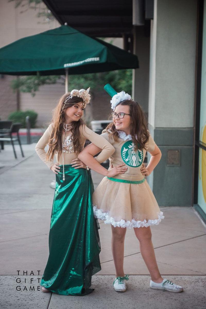 Two girls posing in matching Starbucks costumes, one as a Frappuccino with a whipped cream headband and one as the green Starbucks siren mermaid