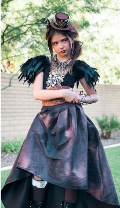 Girl in a steampunk costume with a tiny top hat, feathered shoulders and a high-low skirt