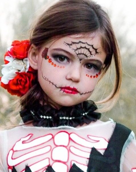 Girl in Day of the Dead sugar skull face paint with red roses in her hair