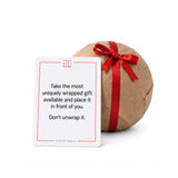 A That Gift Game card beside a wrapped gift, reading Take the most uniquely wrapped gift available
