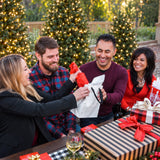 Four adults laughing as one opens a gift during a family Christmas gift exchange with That Gift Game